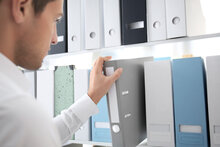 Mann greift nach einem Ordner