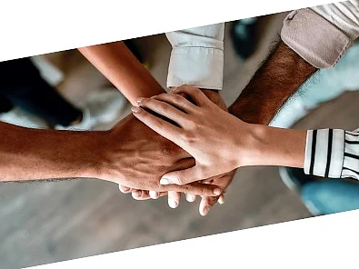 Die Hände verschiedener Personen sind überinander gestapelt, um Zusammenhalt zu zeigen
